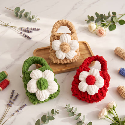 Close-up of artisan handcrafted crochet mini tote bags made from thick yarn. The soft protective pouches display a prominent white 3D flower, perfect for holding small tech accessories.