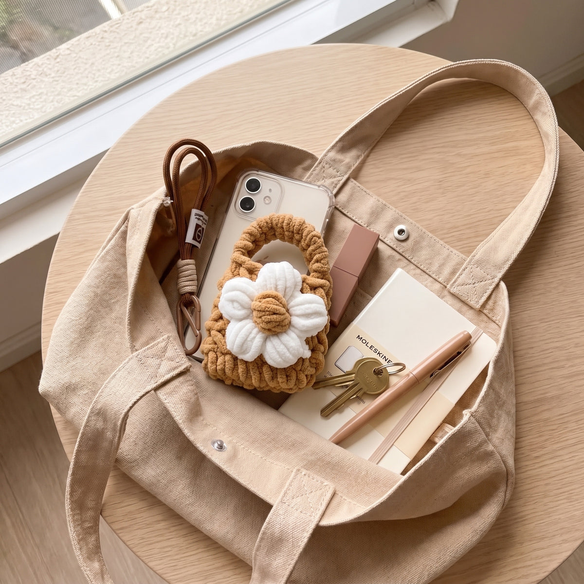 Handmade chunky crochet daisy flower mini pouch placed inside canvas tote bag, showing everyday carry, earbud storage, cute handmade accessory