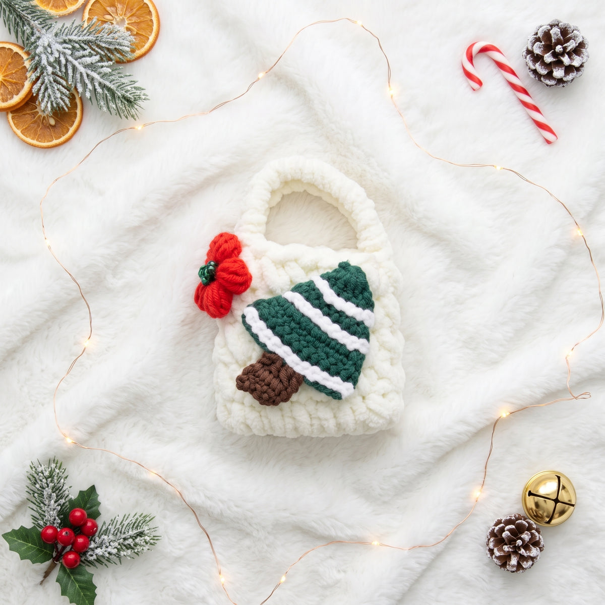 A charming, white knitted tech accessory pouch designed with a festive green Christmas tree and a small red knitted flower. The textured fabric and a functional small carrying handle are clearly visible, presenting a unique way to protect earbuds or small essentials.