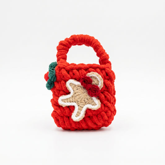 Red knitted mini tote bag for AirPods, decorated with a crochet gingerbread figure, perfect for protecting festive holiday tech accessories.