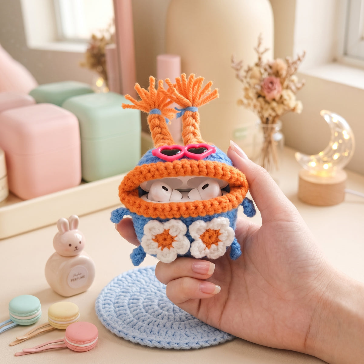 Blue and orange crochet earbud pouch featuring white daisy flowers.