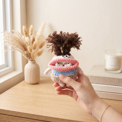 Handmade crochet AirPods case with big googly eyes, pink mouth, and fuzzy monster antennae