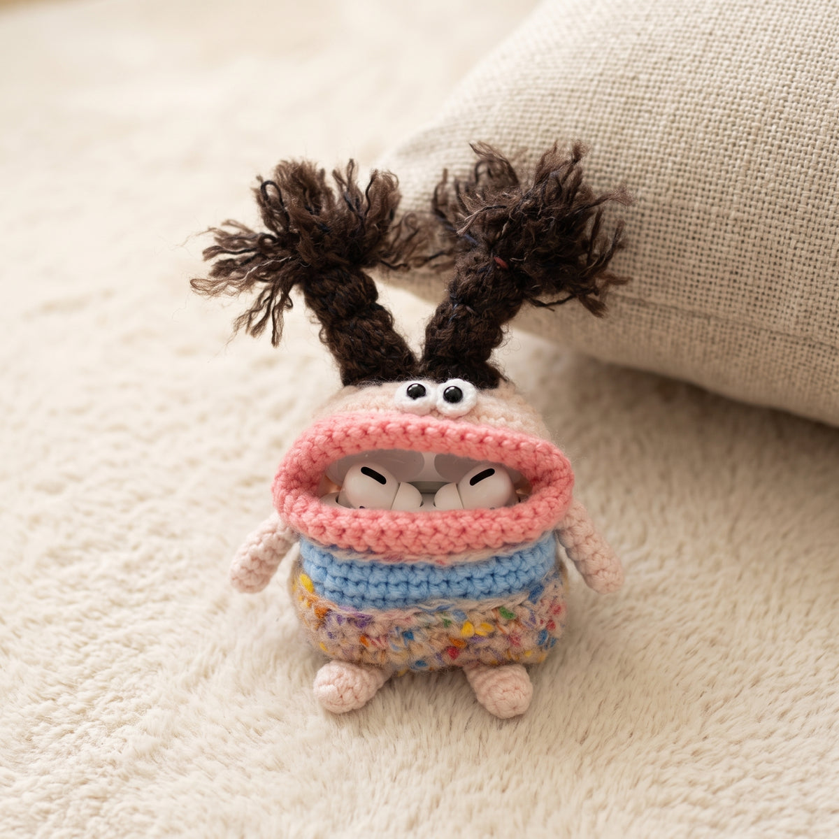 Adorable crochet AirPods case featuring blue and pink yarn, soft texture, and a cute monster face