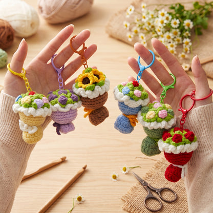 Hands holding assorted handmade crochet flower bouquet keychains, cute knitted floral key charms, aesthetic handmade gift accessory