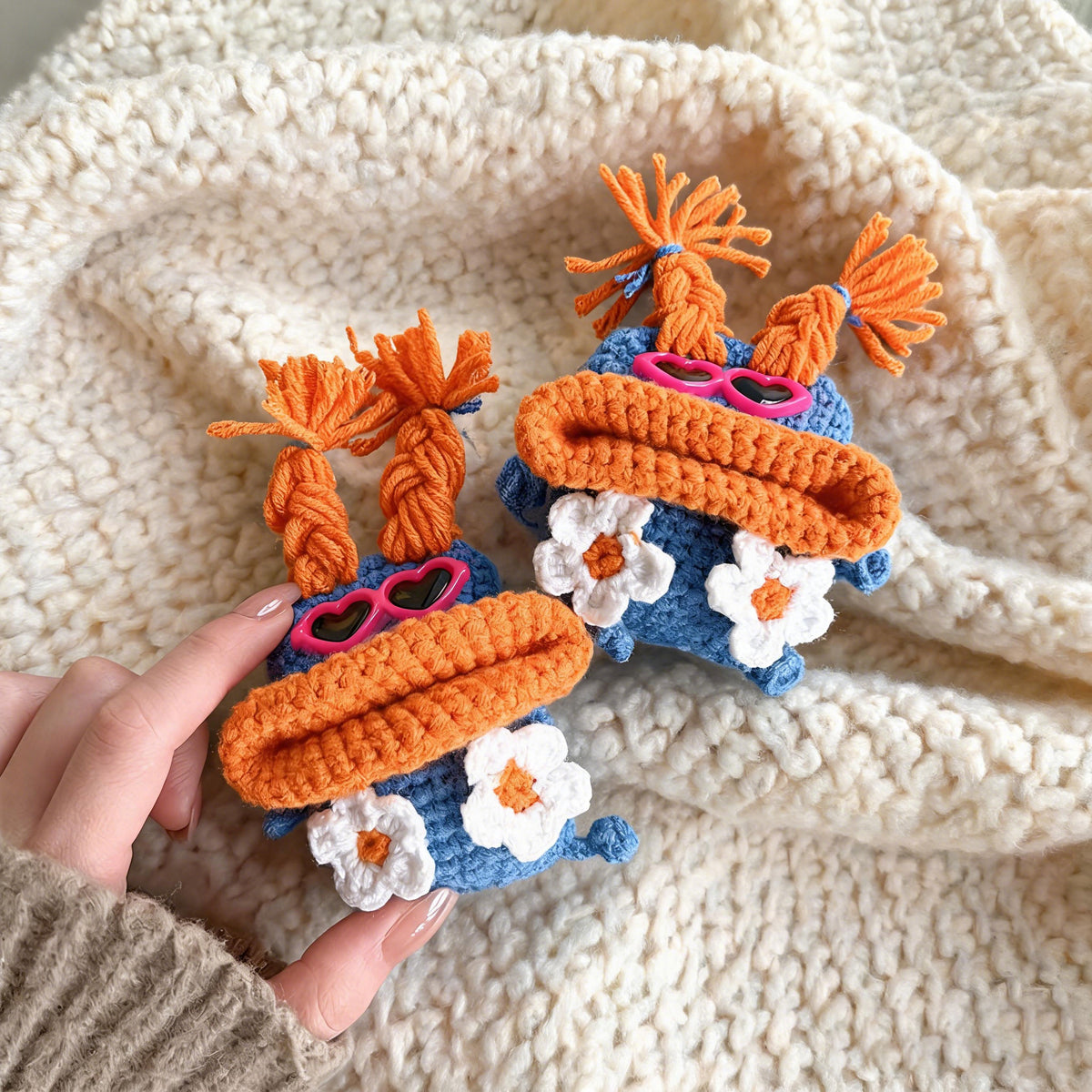 Handmade crochet monster AirPods case in blue and orange.
