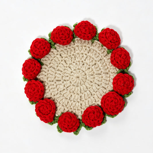 Beige handmade crochet coaster with red 3D roses and green leaves around scalloped edge, flat lay on plain white background, floral drink mat