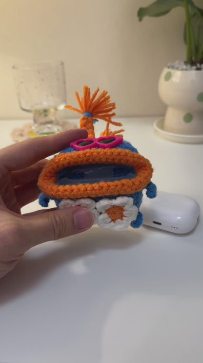 Handmade crochet monster AirPods case in blue and orange, with pink heart glasses and daisies